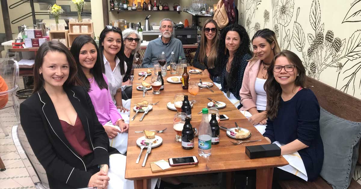 grupo de chicas sentadas en una mesa de un restaurante sonriendo a cámara